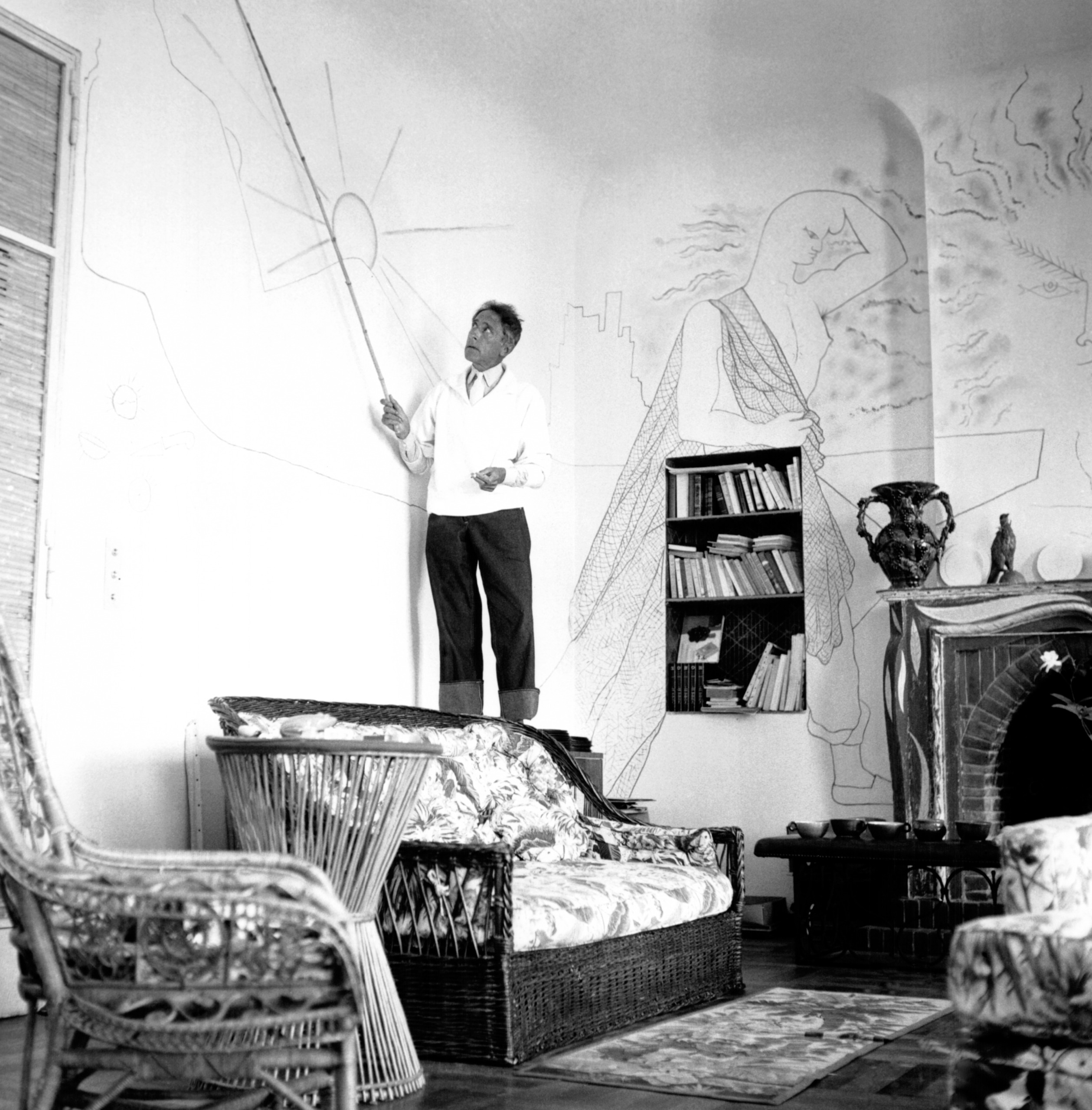 Jean Cocteau standing on the back of a sofa
