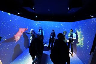 People inside a room projection mapped with content in vibrant blue and red.