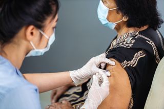 A healthcare professional giving a vaccine to a person.