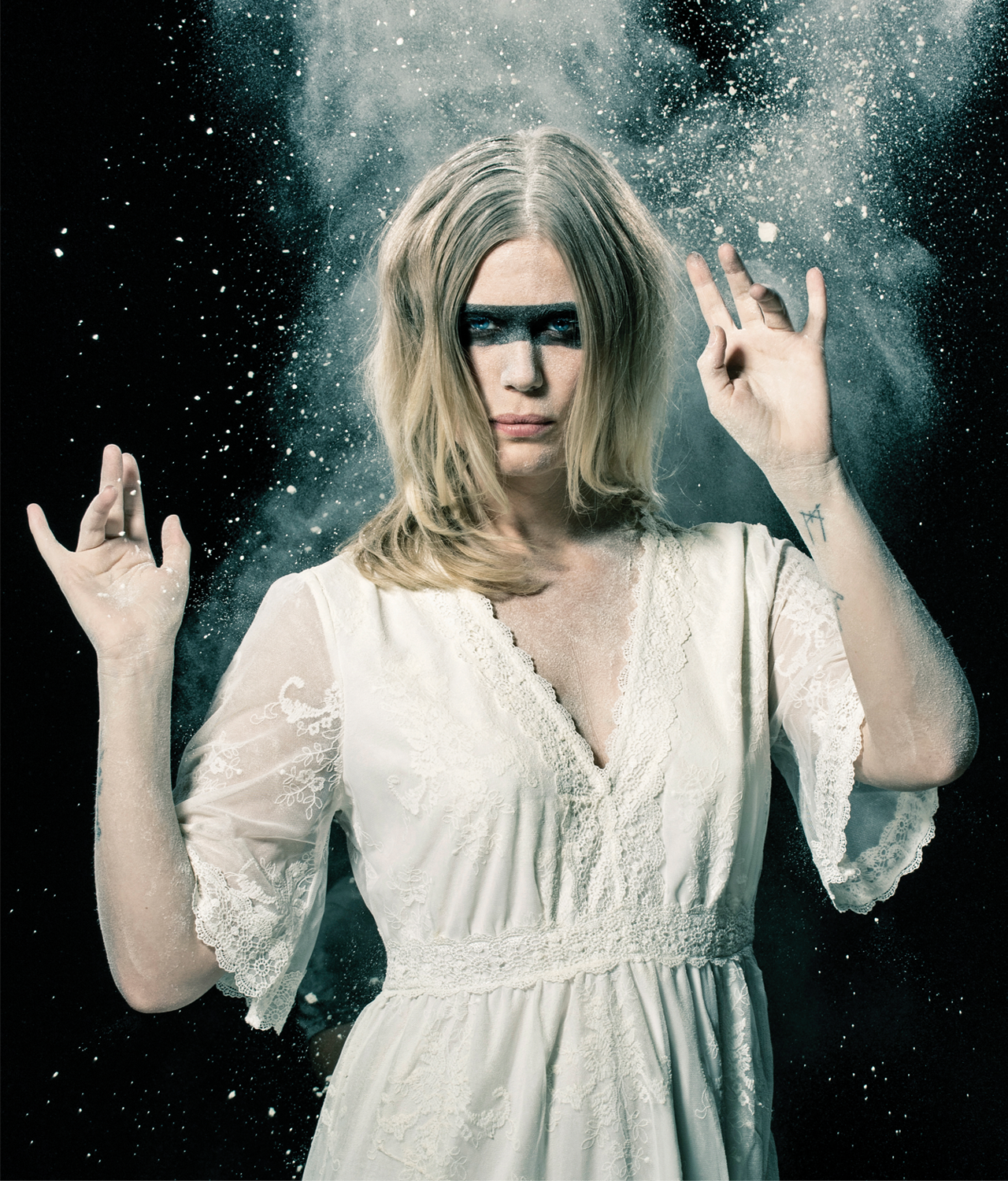 Myrkur in a white dress with a black stripe painted across her eyes