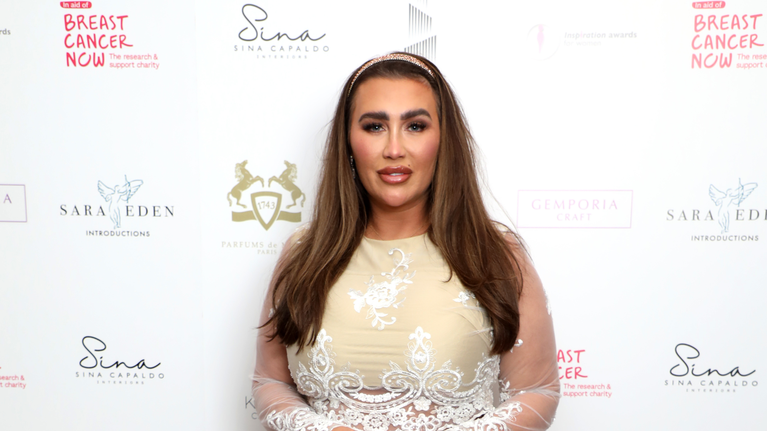 Lauren Goodger at red carpet event wearing gold dress with lace detailing.