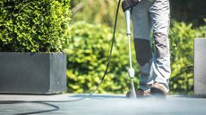 Man cleaning a concrete patio with a pressure washer for article on how to clean rust from concrete