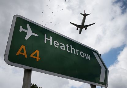 A plane flies over Heathrow Airport.