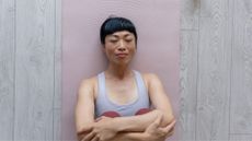 Woman doing Pilates toe taps lying on yoga mat on wooden floor