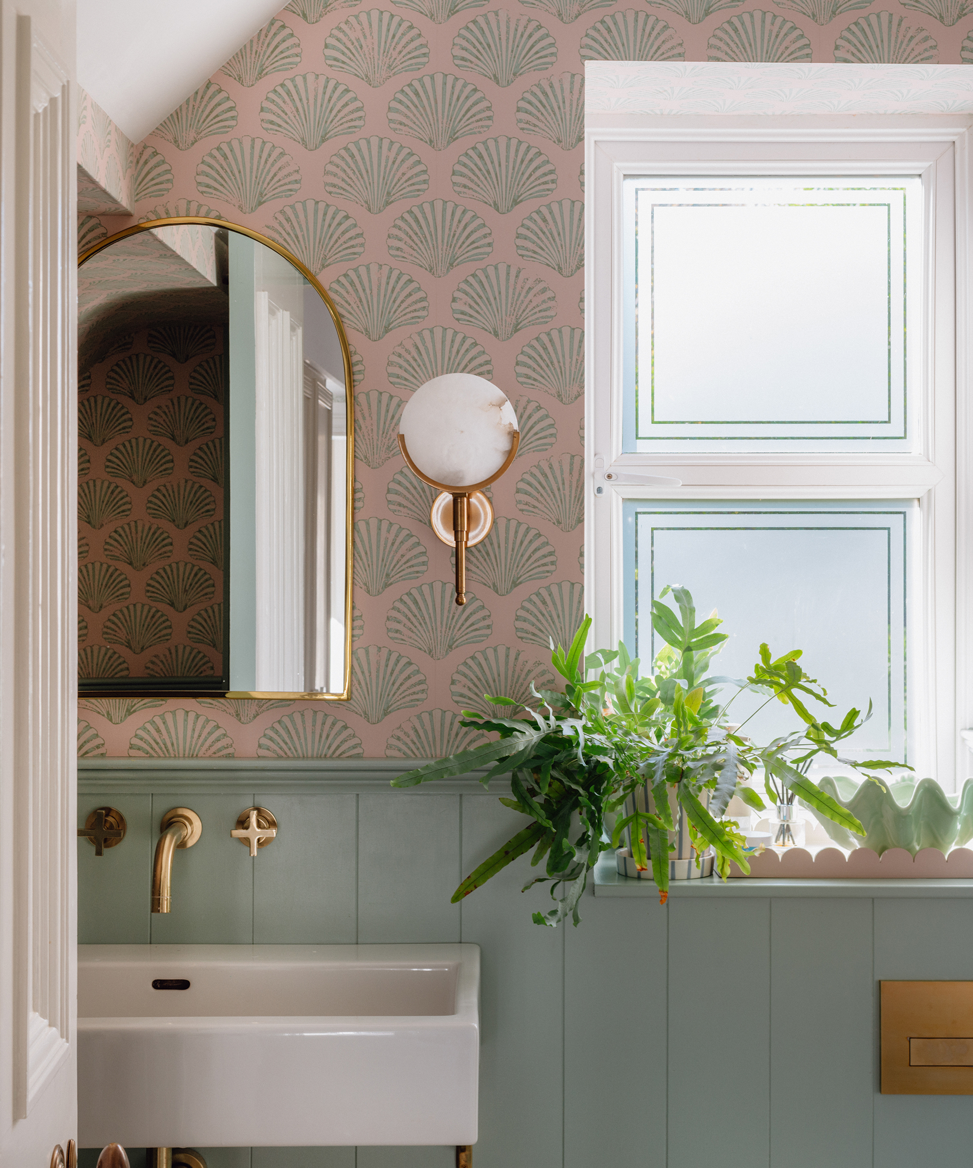 bathroom with shell patterned wallpaper, wall panelling and gold accessories