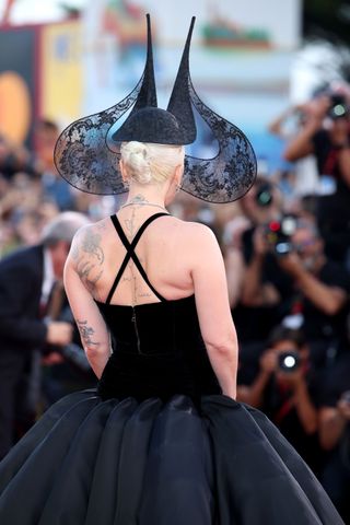 Lady Gaga wears a black lace headpiece at the Joker premiere with a black dress.