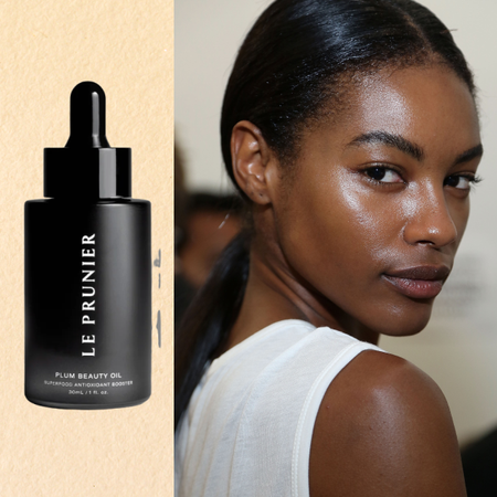A woman with a low ponytail and glowing skin, next to two bottles of face oil. 
