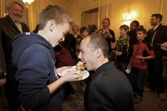 Sven Nys receives a mouthful of cake from his son Thibault as Prime Minister Elio Di Rupo receives the Belgian team that won the Cyclocross World Championship race in Koksijd