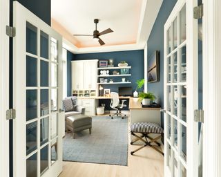 A bright living room with home office area and ceiling fan
