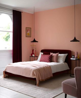 bedroom with pink walls and simple red velvet bed, pink bedding and deep red floor to ceiling curtains