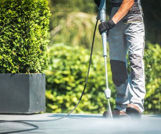 Man cleaning patio paving slabs using a pressure washer