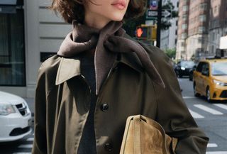 Woman in trench coat and suede bag.