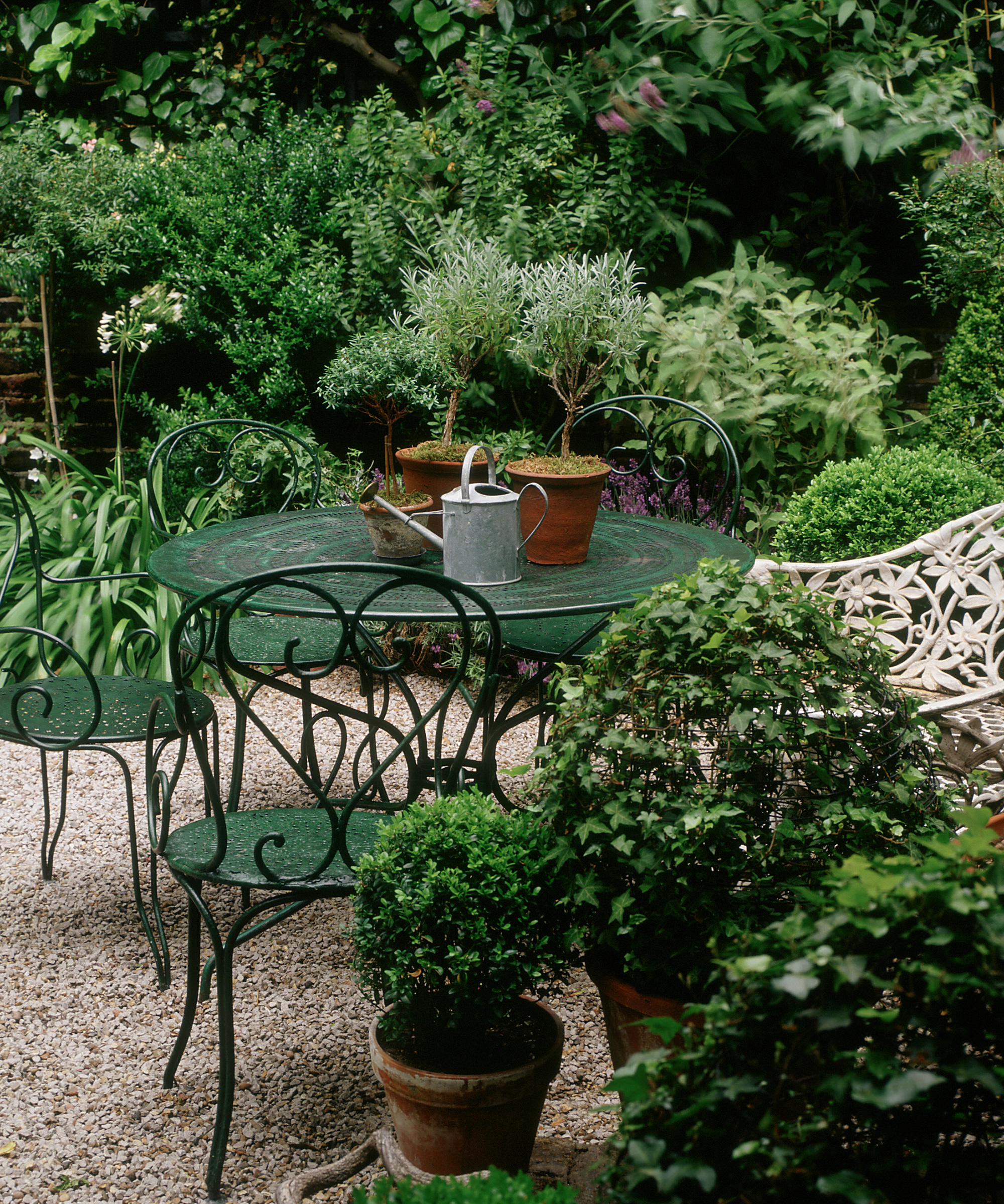 Patio planter ideas on a gravel patio with green metal round table and chairs.