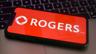 A phone bears the Rogers Communications logo on a red background, while resting on a Macbook keyboard