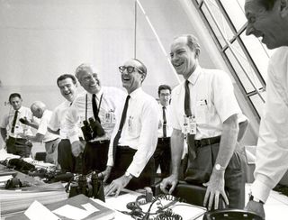 Apollo 11 mission officials relax in the Launch Control Center following the successful Apollo 11 liftoff on July 16, 1969. Second from left (with binoculars) stands Dr. Wernher von Braun, Director of the Marshall Space Flight Center.