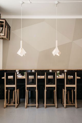 A table with four black and natural wood chairs under two abstract light fittings