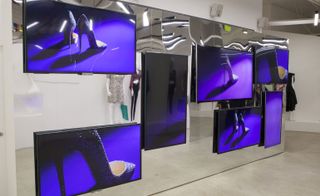 Large screens displaying a pair of glittery shoes against a blue background
