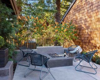 Sleek gray patio furniture ideas in a small concrete patio area with brick wall and metal railings.