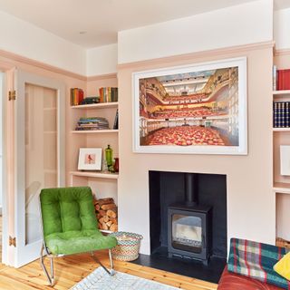 Pink living room with black log burner and green chair