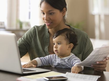 Mother working on computer with baby on her lap