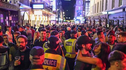 Police make their way through crowds of revellers during the pandemic in Soho, London
