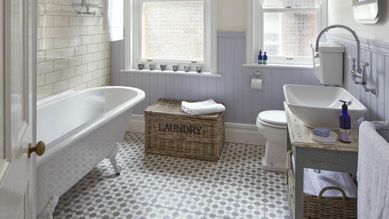 浴室地板瓷砖思想的一个例子，显示灰色和白色马赛克地砖在有白色的自由站立浴和洗衣篮的浴室里