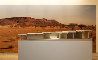 Architectural model which slowly increases in height, with a background showing a desert scene