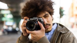 Man holding a camera taking photographs in urban setting