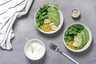 a salad of avocado, eggs, sweetcorn and greek yoghurt on a grey slate background