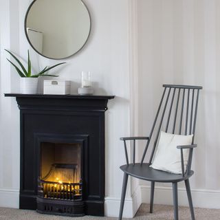 living room with white walls and black fire place with mirror and chairs