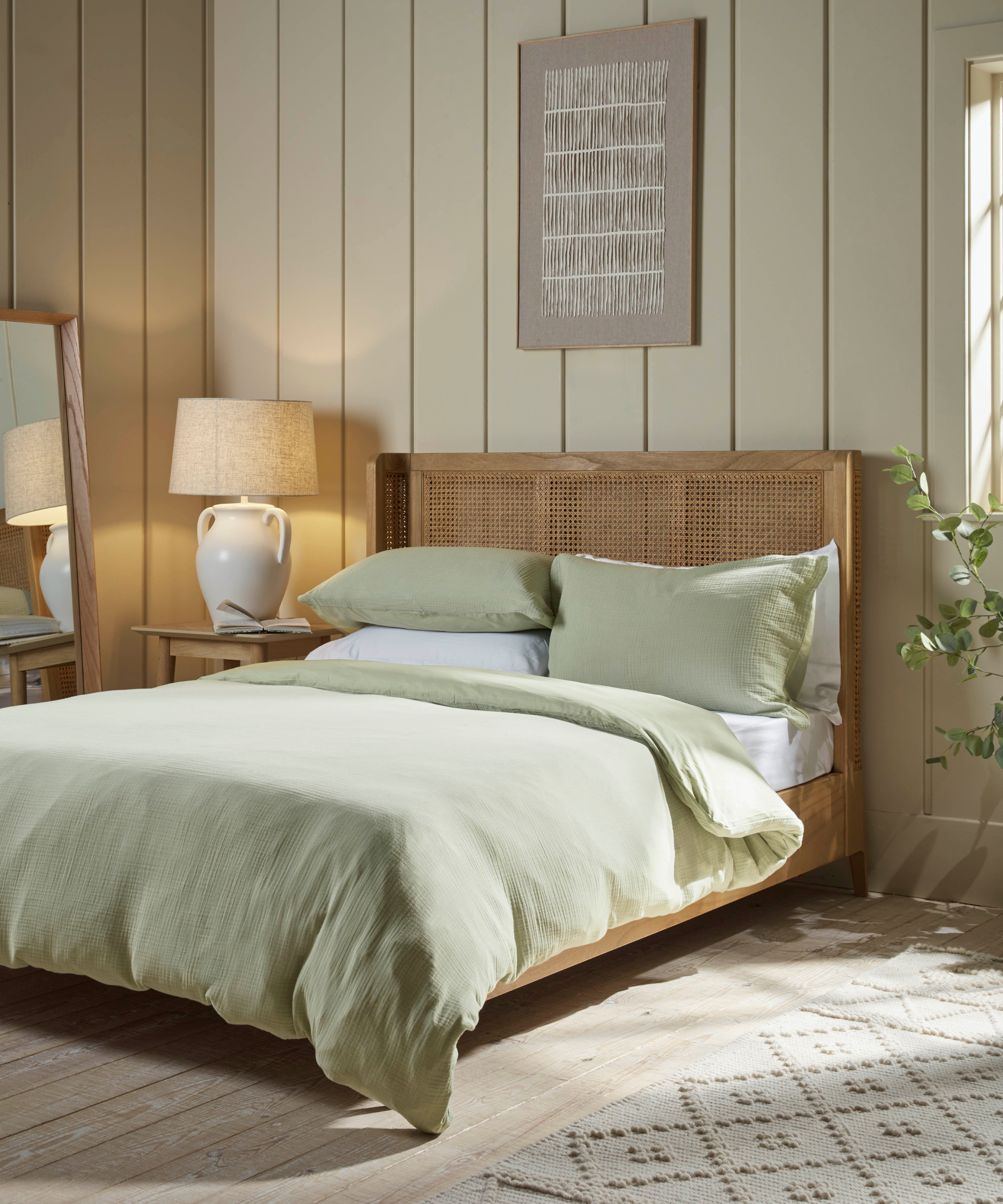 green muslin bedding on wooden and rattan framed bed