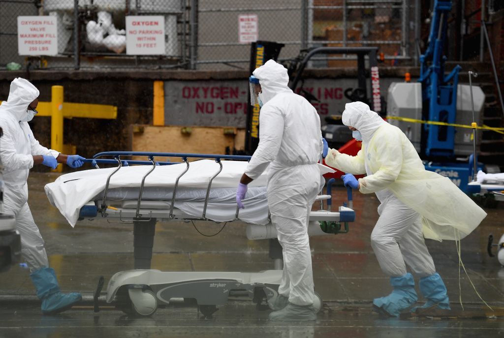 Medical personnel move a deceased patient to a refrigerated truck serving as make shift morgues at Brooklyn Hospital Center on April 09, 2020 in New York City. 