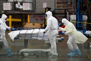 Medical personnel move a deceased patient to a refrigerated truck serving as make shift morgues at Brooklyn Hospital Center on April 09, 2020 in New York City. 