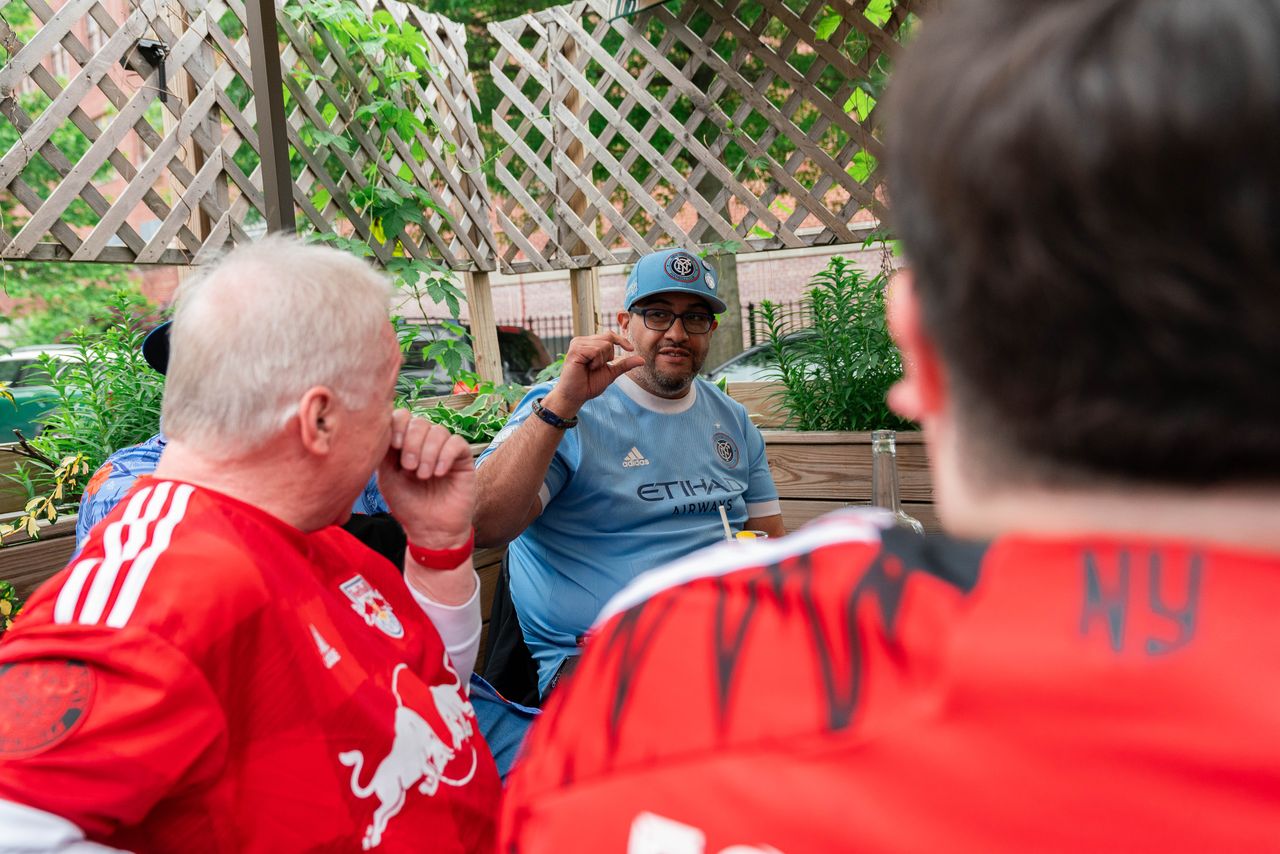 New York City FC fan Felix Palao debates with New York Red Bulls fans outside a restaurant in Queens