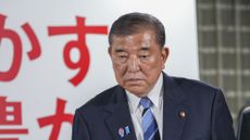 Japan's prime minister and president of the Liberal Democratic Party (LDP), looks at TV news as he leaves the party's headquarters following the upper house election in Tokyo