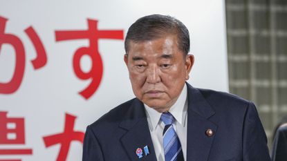 Japan's prime minister and president of the Liberal Democratic Party (LDP), looks at TV news as he leaves the party's headquarters following the upper house election in Tokyo