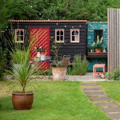 a black shed painted with bright colours around the window and on the door