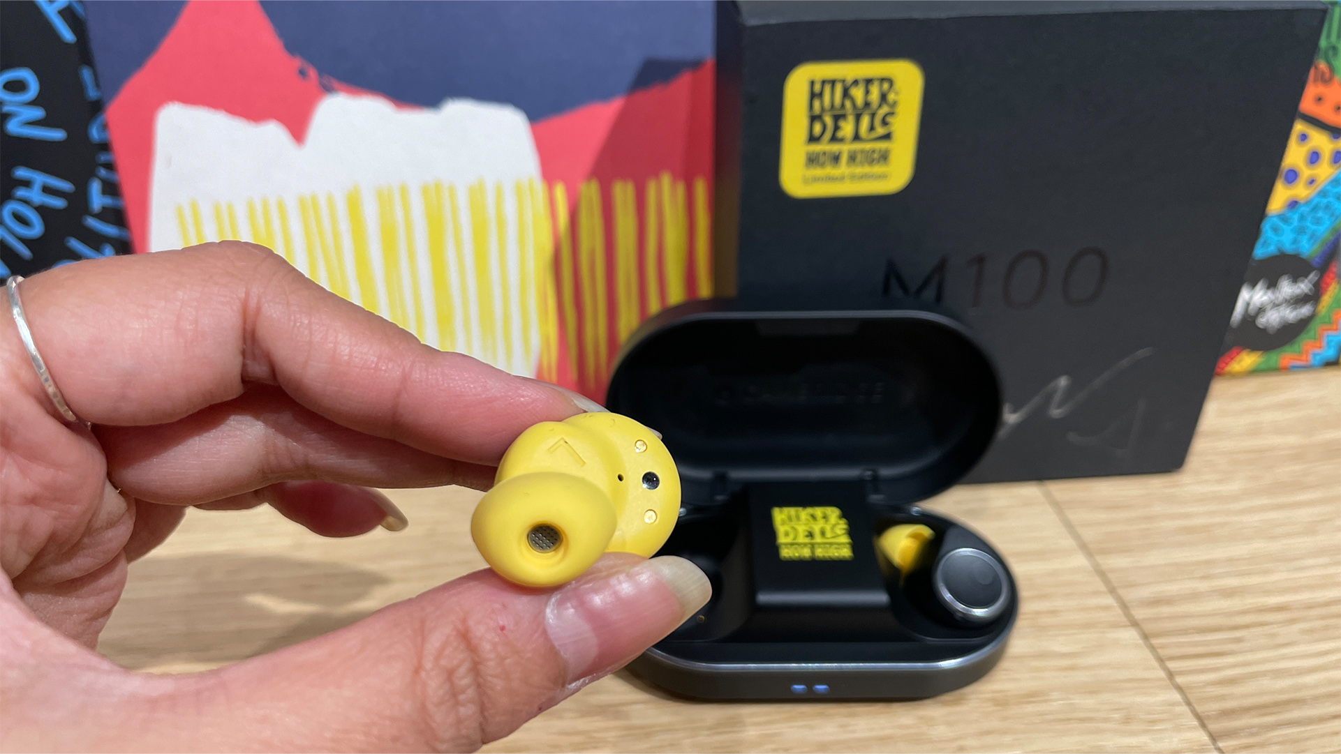 Cambridge Audio Melomania M100 wireless earbuds with alternate yellow tip in hand