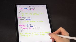 A photograph of the someone writing on the Apple iPad Air with an Apple Pencil
