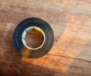 A roll of black tape on a wooden surface