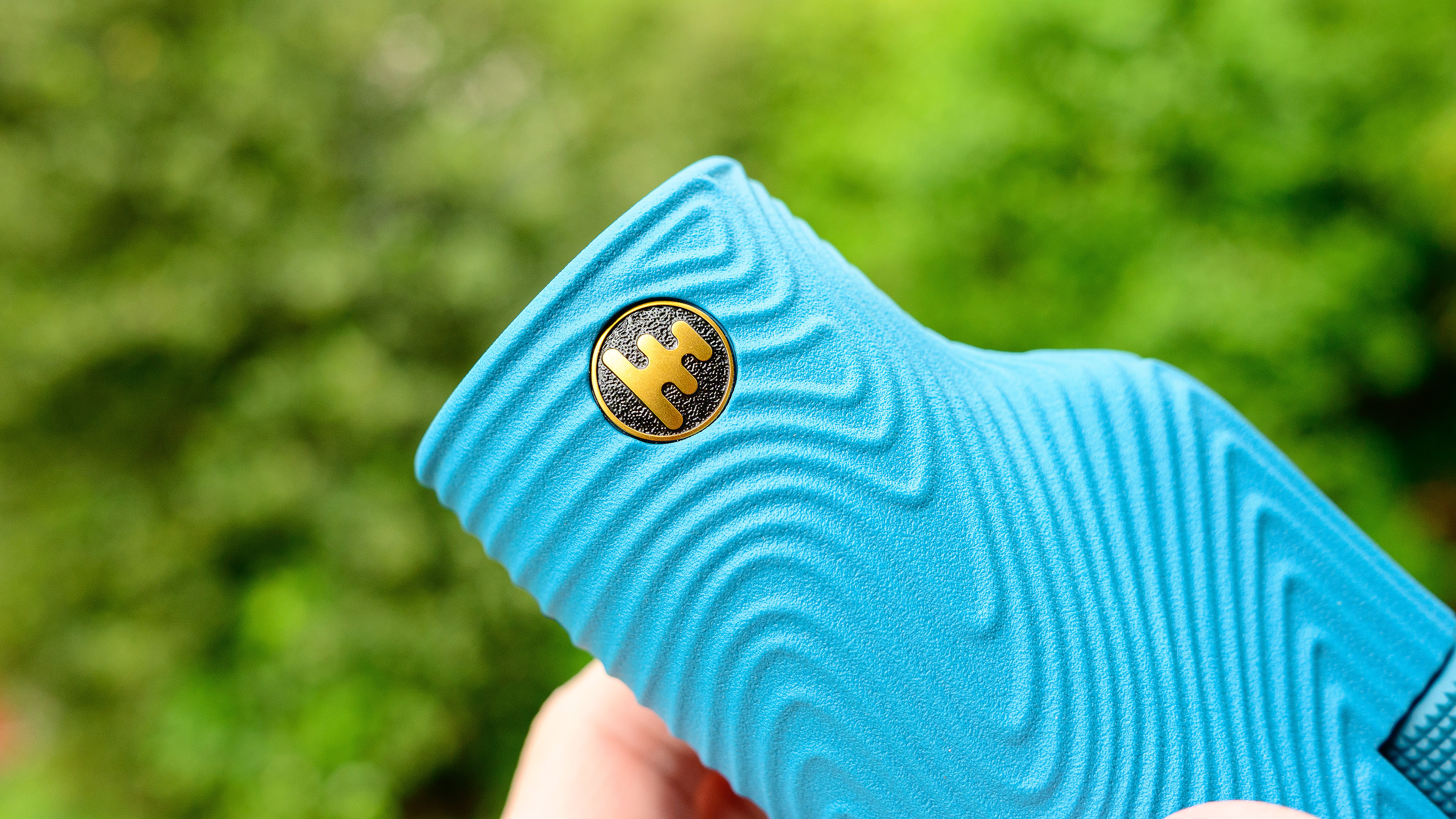 A close-up of the Nocs Field Tube monocular logo.  Depicted on the user's hand against a green background.