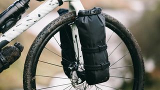 A shot of the black Tailfin dry bag strapped to the fork of a Canyon Grizl
