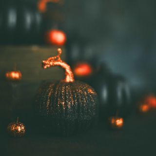 a black glittery pumpkin with a spooky black and orange background