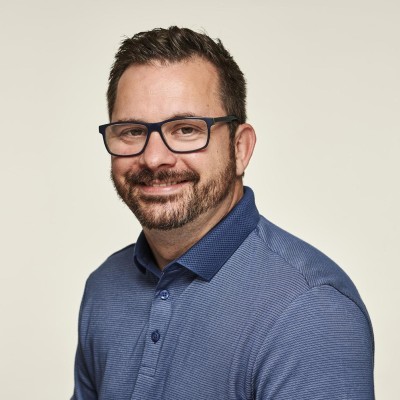 male with dark short hair, black glasses wearing blue shirt