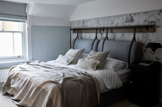 blue and white bedroom with custom built headboard, gray and oatmeal blankets and bed pillows, wallpaper behind headboard, blue blind