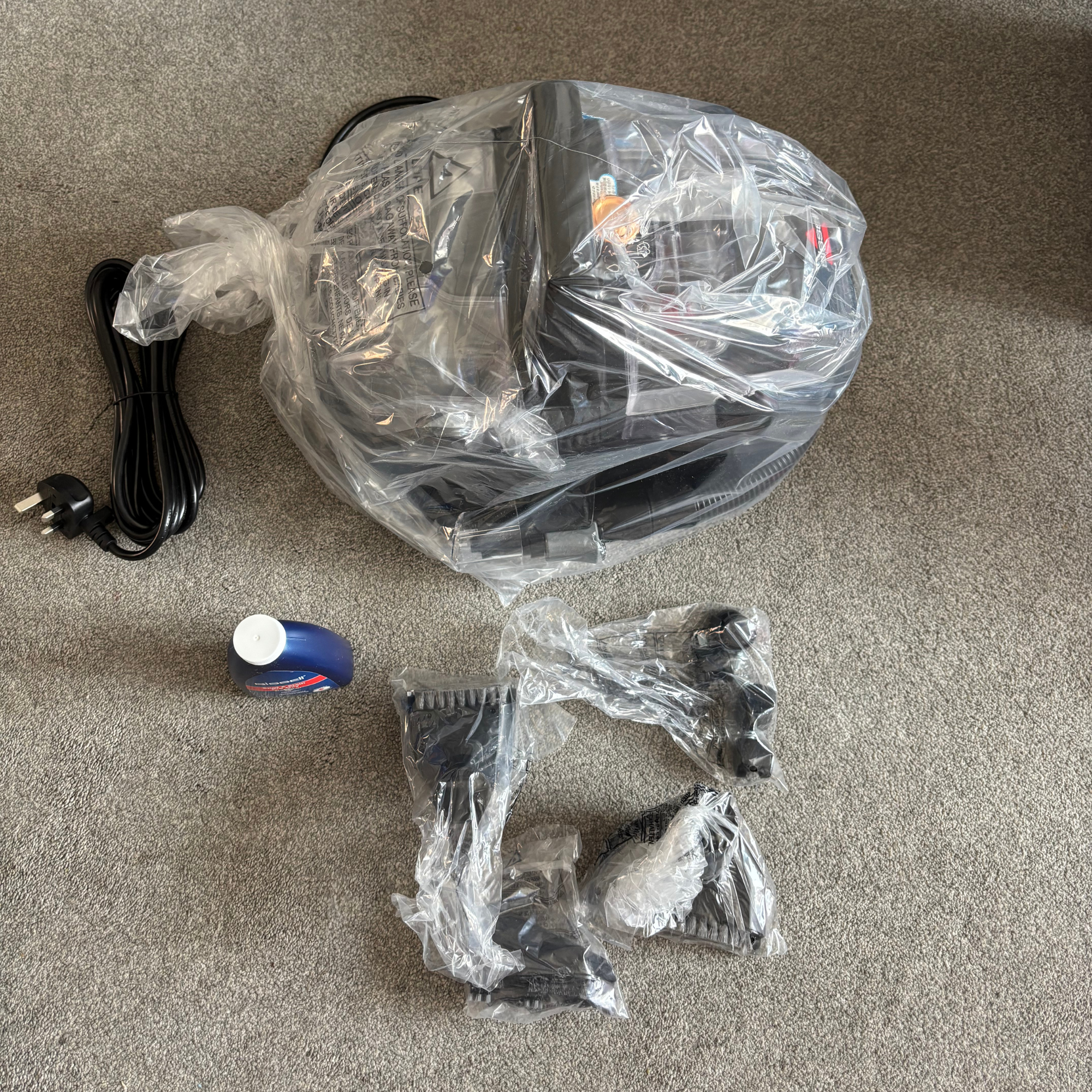 Bissell SpotClean HydroSteam contents out of box, wrapped in plastic packaging
