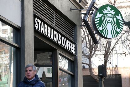 A man walks outside of a Starbucks.