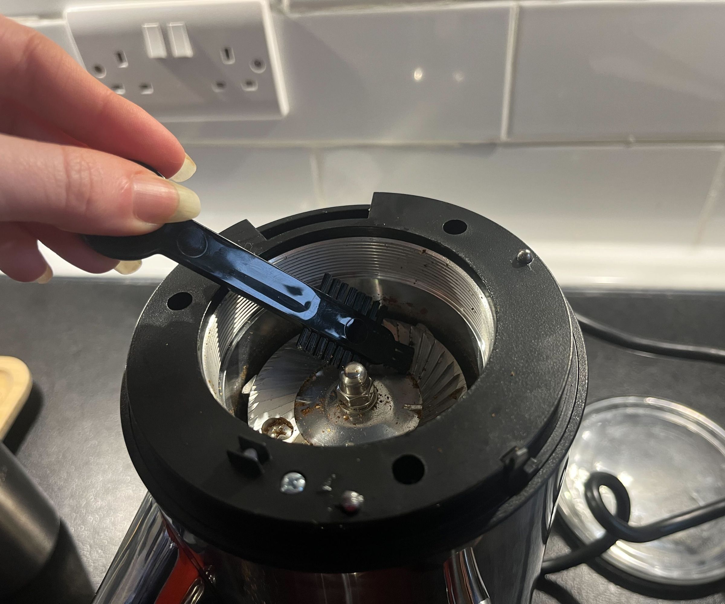 Using a small brush to brush the burrs of a coffee grinder