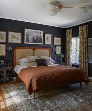A bedroom curtain idea with long drapes on a short window, dark blue walls and a white ceiling
