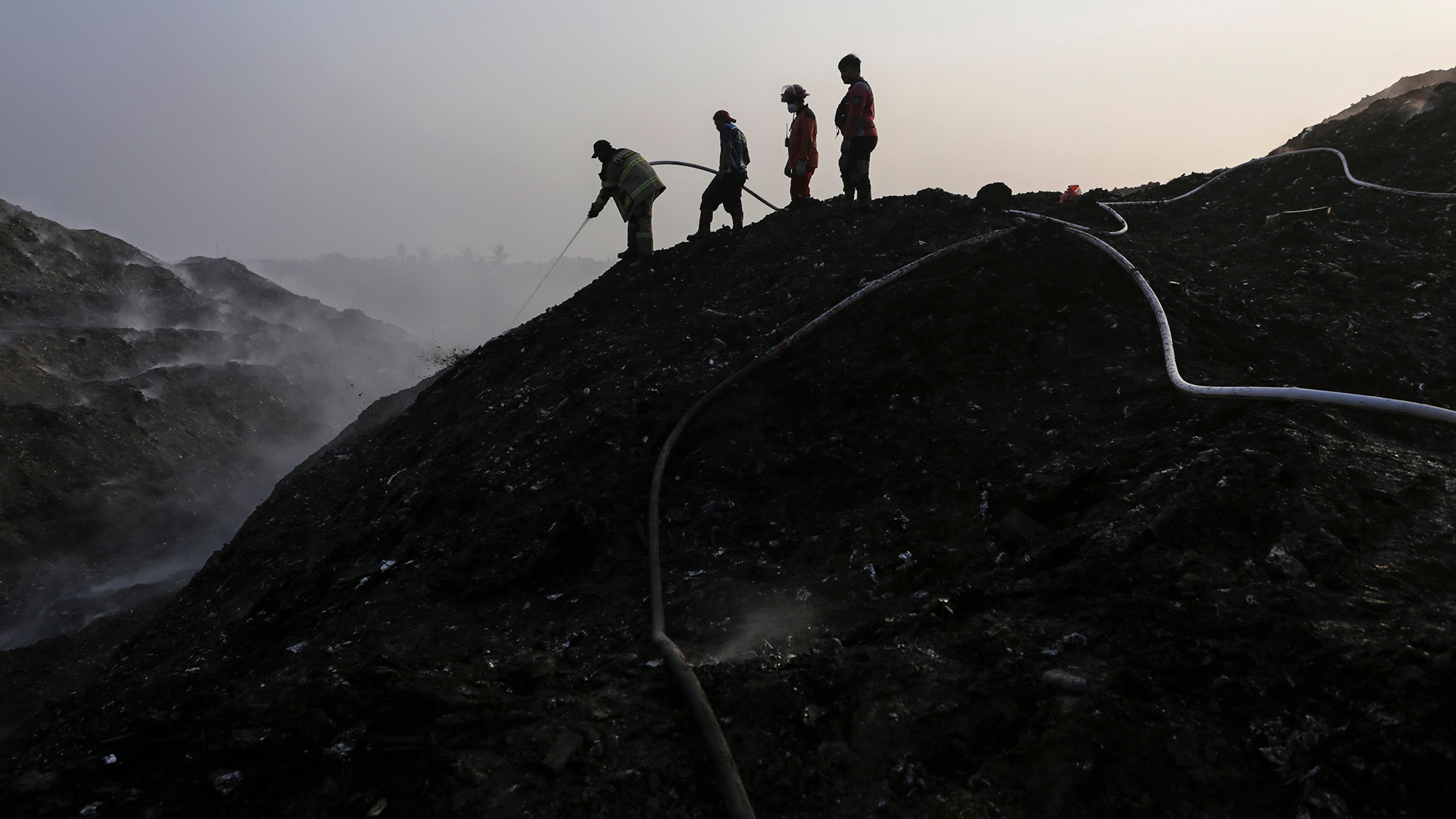 Firefighters work to extinguish the blaze at Jatiwaringin landfill on the outskirts of Jakarta, Indonesia